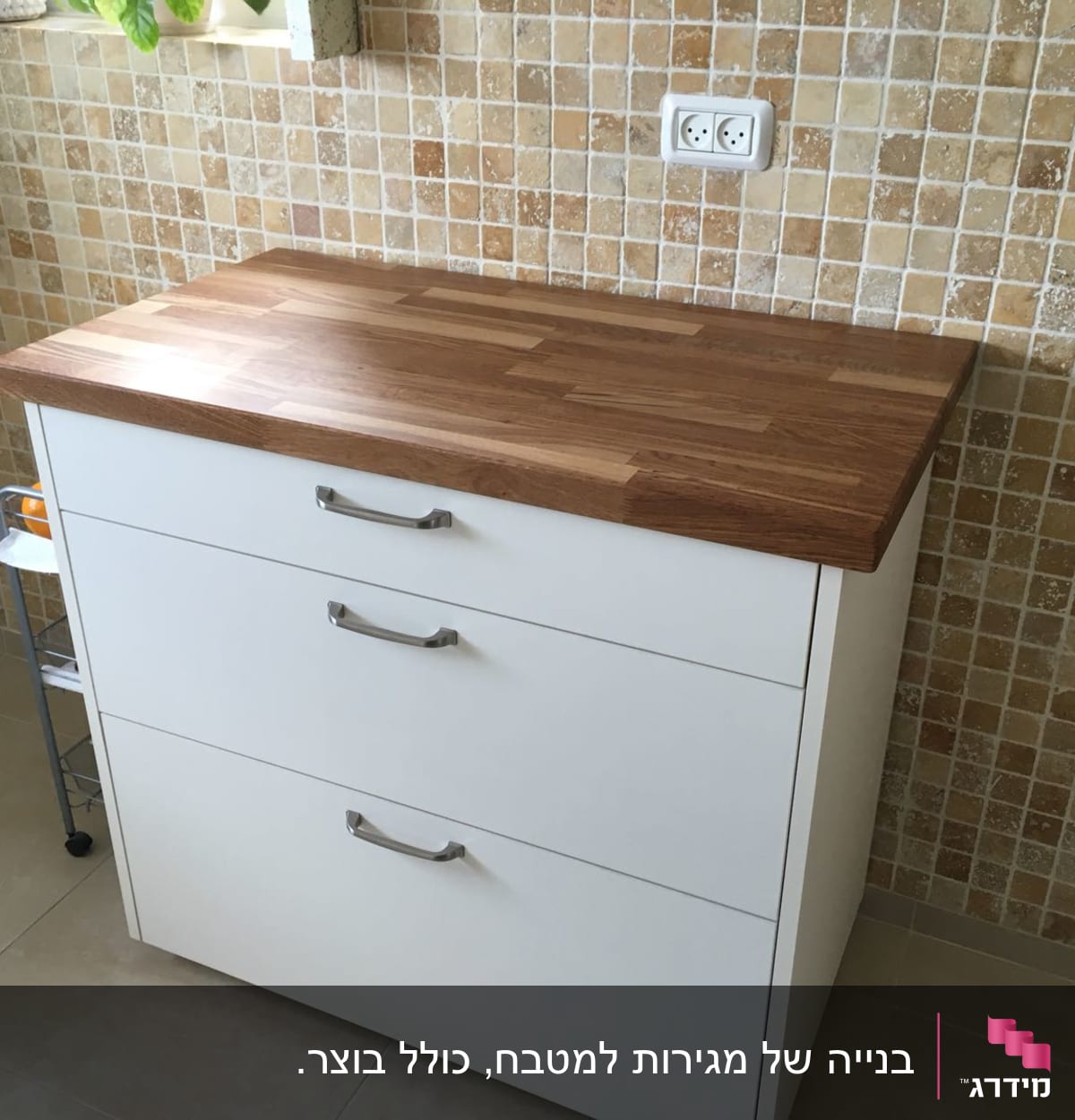 ארון מטבח לבן עם משטח עץ על רקע קיר אריחים